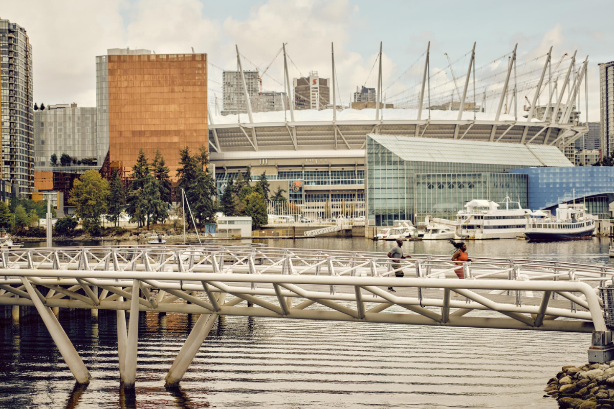 https://www.discovercanadatours.com/wp-content/uploads/2026/05/©DestinationVancouver-KindredandScout-CoupleRunningatOlympicVillage-1200x800-1.png